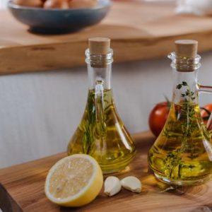 Fresh garlic and lemon with olive oil bottles, perfect for Italian cuisine. Captures freshness and flavor.