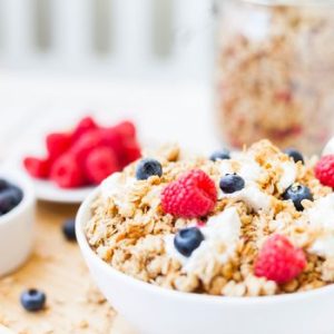 Healthy granola breakfast bowl topped with fresh raspberries and blueberries.